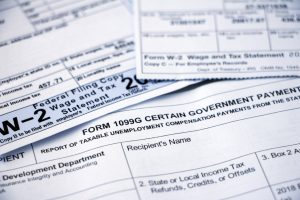 Closeup of overlapping Form 1099G Certain Government Payouts and W-2 forms.